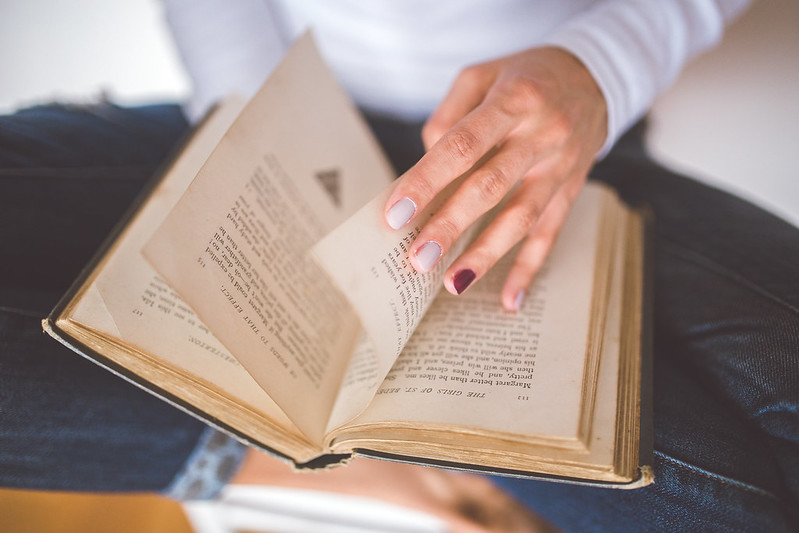 Hand turning pages of a book. Historical Consultancy and Historical Research.